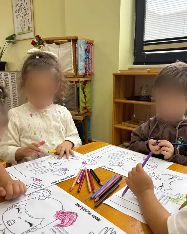 Değerler eğitimi etkinliğinde hapşırma adabı çalışma kâğıtlarını boyayan çocuklar
