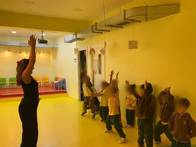 Drama dersinde öğretmenleriyle kollarını kaldıran çocuklar