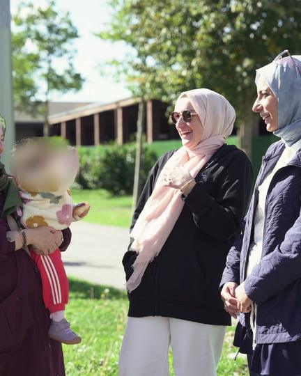 Bisiklet etkinliğinde sohbet eden veliler ve kucakta bir bebek