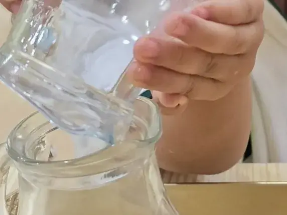 Cam kaplarla su döken bir çocuğun elleri