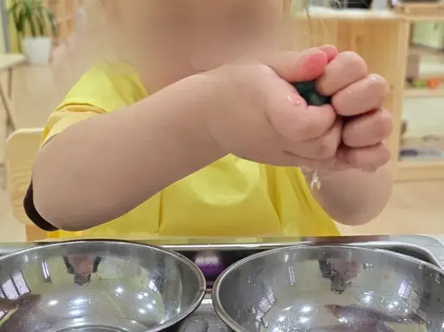 Metal kaselerin üzerinde süngeri sıkan bir çocuğun elleri