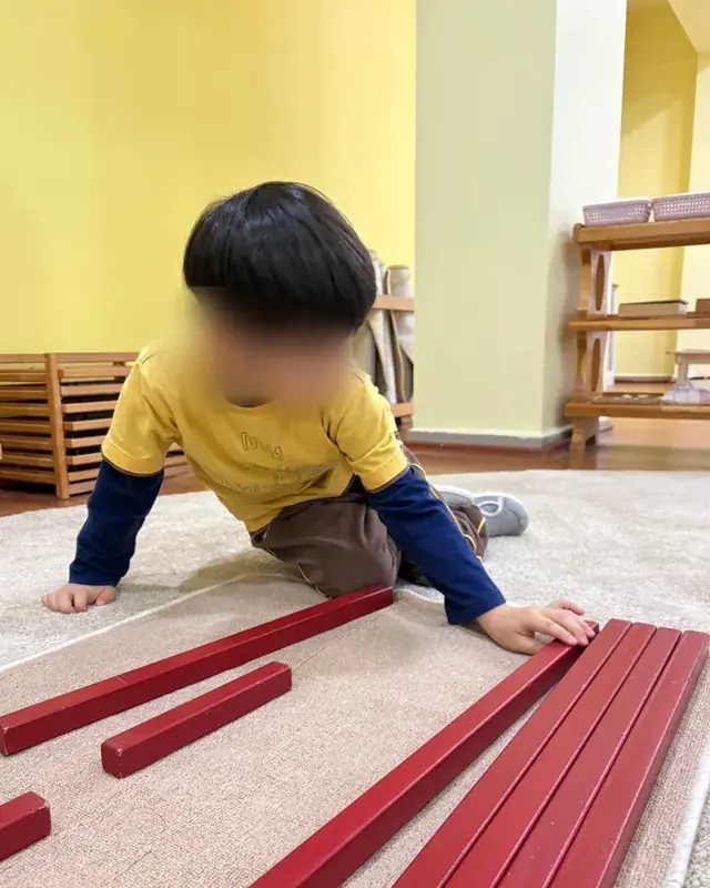 Kırmızı çubukları boy sırasına dizen bir çocuk